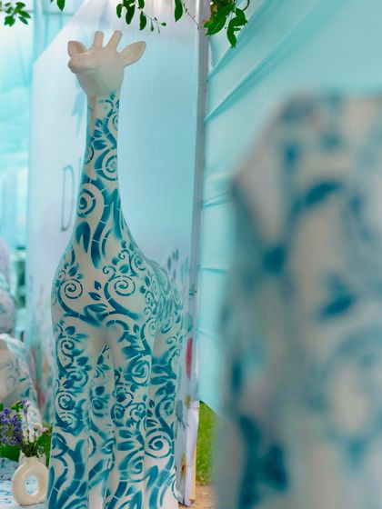A close-up of the custom-painted giraffe sculpture, a key element of the whimsical Dior-inspired animal theme that made this Mehendi so unique.