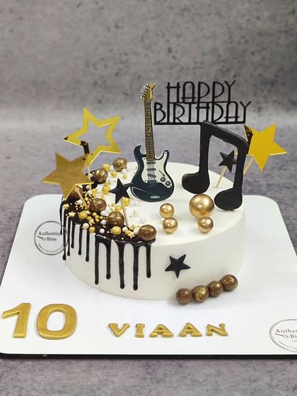 A rockstar cake for a music lover. This design features a guitar, musical notes, and stars, all in a cool black and gold theme.