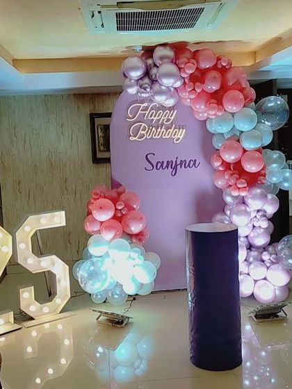 A lovely 25th birthday setup with a pastel purple backdrop, a balloon arch in pink and blue hues, and a large '25' marquee number.