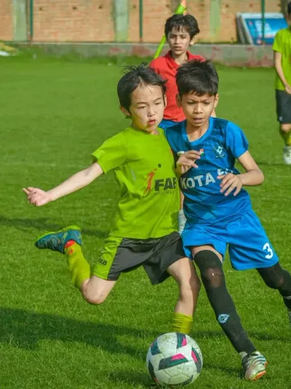 An intense moment as two players challenge for the ball, both showing great balance and control.