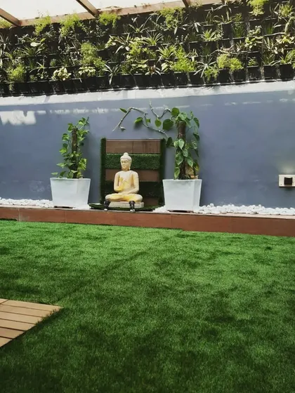 A terrace garden is incomplete without a Buddha statue. Here, it is placed in front of a large vertical garden, creating a wall of green.