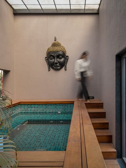 A jacuzzi and plunge pool area, tucked away in a private corner of the villa. The space is surrounded by wood decking and lush plants, with a skylight above, creating a serene, spa-like retreat.