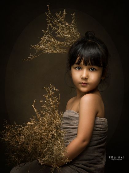 A stunning fine art portrait of a young girl. The moody lighting, earthy tones, and her direct gaze create a powerful and artistic image.