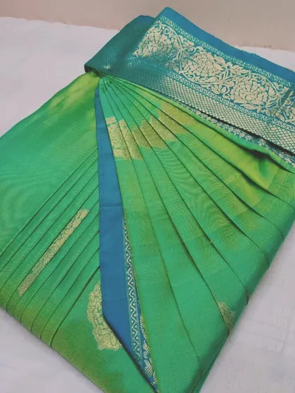 A sea green silk saree with a blue border, pleated and ready.