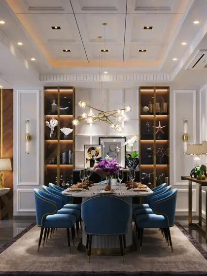 We love to infuse spaces with personality. This opulent dining room features plush velvet chairs in a striking blue, a modern chandelier, and curated art, creating a vibrant setting for memorable gatherings.