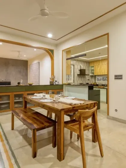 A complete view of the Villa 17 dining space, with a custom wooden bench and chairs. The area is defined by patterned floor tiles and overlooks the kitchen.