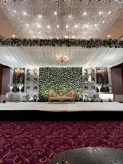 A wide shot of the reception hall, showing the grand scale of the Walima decor. The flower wall and crystal ceiling create a truly spectacular setting.