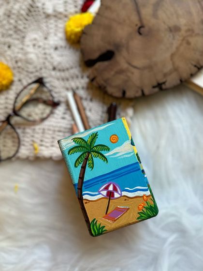 The Summer side of the four-seasons pen stand, featuring a relaxing beach scene with a palm tree and umbrella.