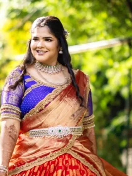A client glowing in her bespoke engagement half saree. The vibrant red and blue Kanjivaram fabric creates a stunning traditional look, customized to make her feel special on her big day.