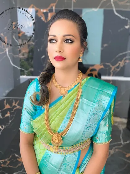 A sophisticated engagement look featuring a stunning green and blue Kanjeevaram saree. I created a classic look with sharp winged eyeliner, a bold red lip, and a stylish side fishtail braid.
