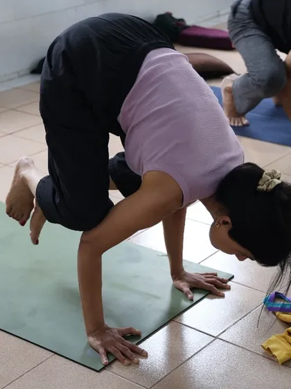 A student practices Bakasana, the crow pose. Our classes help you build the foundational strength required for such balancing postures.