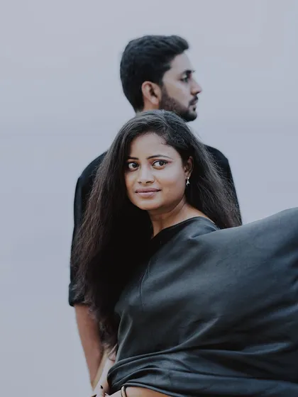 A striking portrait from a pre-wedding shoot, where the woman looks towards the camera with her partner in the background.