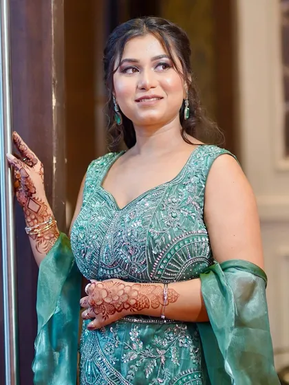 An elegant pose showing off the details of her green outfit and the complementary makeup.