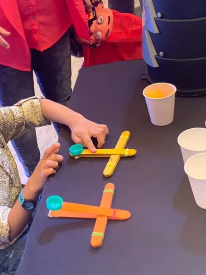 A young boy gets ready to launch his catapult. The focus and excitement are palpable as he prepares to see his engineering project in action.