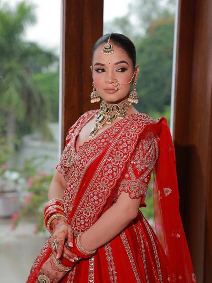 A portrait of a bride in a classic red lehenga, looking serene and beautiful. The deep red color and silver embroidery are a timeless combination.