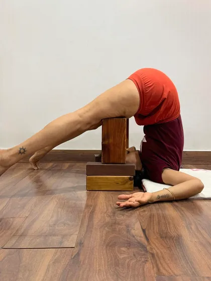 This is a supported Halasana with the back on stacked blocks. The generation of prana in the human system can be compared to electrical energy. Pranayama makes the fibers of the lungs act as turbines, generating energy that is stored in the chakras and distributed throughout the system.