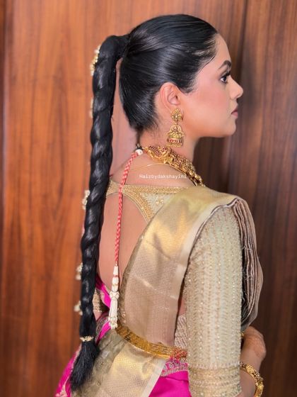 This profile view highlights the sleekness of the high ponytail and the length of the traditional braid, a very regal and powerful bridal look.