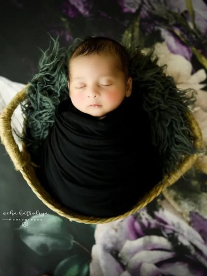 An aerial shot that showcases the beautiful contrast between the baby's black wrap and the vibrant floral floor drop.