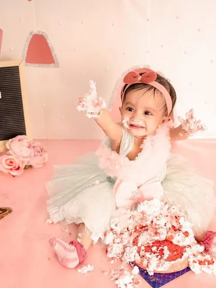 A princess deserves a royal mess! This little girl is joyfully smashing her first birthday cake in our pink castle-themed studio setup, complete with a beautiful dress and all.