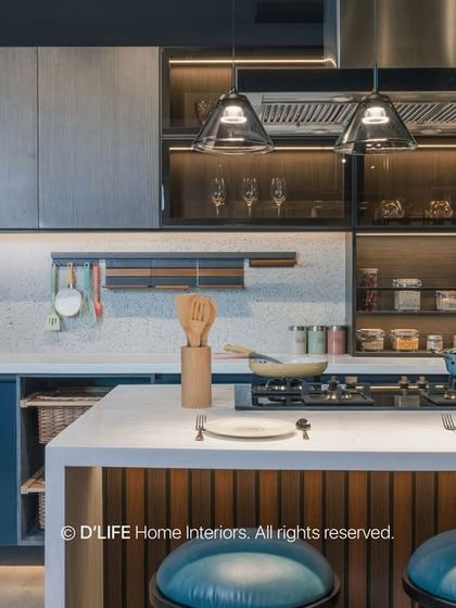A stylish island kitchen combining dark blue and wood-grain cabinets with a white countertop. The open shelving and glass-front upper cabinets provide both storage and display space.