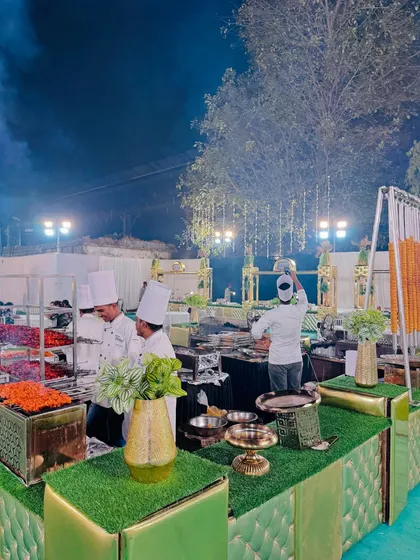 A wide shot of the barbecue area, where chefs prepare a variety of grilled items, with smoke adding to the authentic outdoor cooking atmosphere.