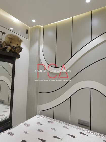 A bedroom designed with flowing, cursive-inspired wall panels. The white and grey tones create a calm and soothing environment, while the unique wall treatment serves as a bespoke piece of architectural art.