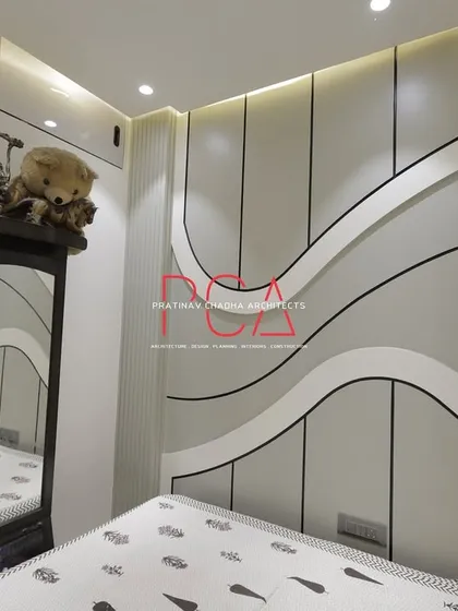 A bedroom designed with flowing, cursive-inspired wall panels. The white and grey tones create a calm and soothing environment, while the unique wall treatment serves as a bespoke piece of architectural art.