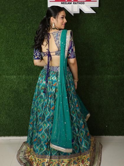 A back view of a client in a beautiful teal printed lehenga with a heavily embroidered blouse.