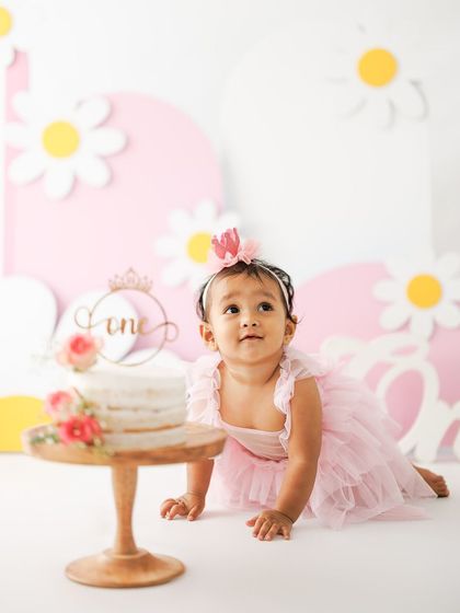Getting ready to dive in. This shot captures the moment of anticipation right before the cake smash begins, with the birthday girl crawling towards her beautiful first birthday cake.