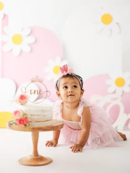 Getting ready to dive in. This shot captures the moment of anticipation right before the cake smash begins, with the birthday girl crawling towards her beautiful first birthday cake.