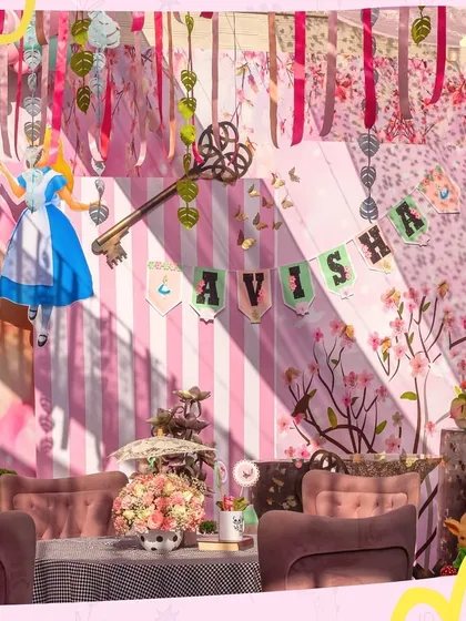 A whimsical setup for an Alice in Wonderland party, featuring a cozy lounge area for guests. The hanging keys and character cutouts add to the fantastical, mad-tea-party feel.