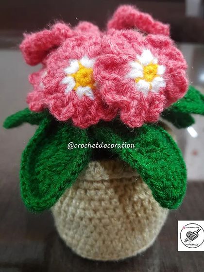A lovely crochet flower basket with pink flowers, a charming alternative to a standard pot.