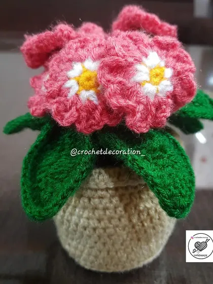 A lovely crochet flower basket with pink flowers, a charming alternative to a standard pot.