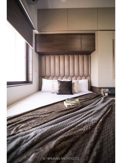 This compact bedroom is designed to feel cozy and enveloping. The upholstered headboard and overhead cabinets maximize storage while creating a snug sleeping nook.