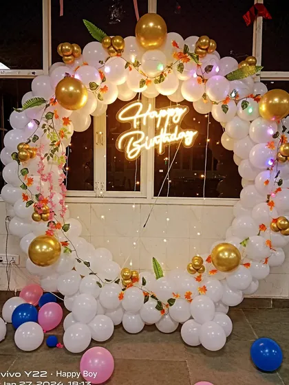 A beautiful white balloon ring decorated with gold chrome balloons and artificial vines. This setup has a fresh and elegant feel, perfect for any age.