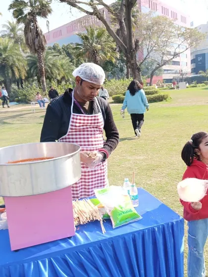 A child delighted with a fresh stick of cotton candy at an outdoor park event. The candy floss machine is always a visual and tasty attraction.