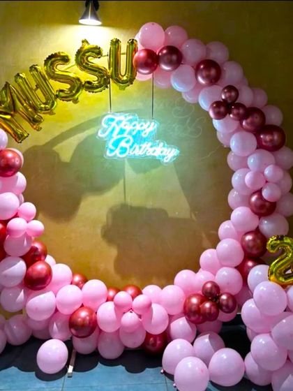 A romantic balloon arch in shades of pink and metallic red for a girlfriend's 21st birthday. The setup is personalized with foil balloons for a nickname 'Missu' and the number '21'.