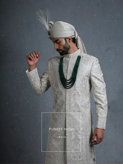 A closer look at the ivory paneled sherwani, highlighting the zardozi finesse and the way the emerald necklace complements the intricate handwork. This is a garment of legacy.
