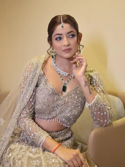 A seated portrait of the same party look, showing how the makeup looks from a different angle. The winged eyeliner and soft hairstyle create an elegant and modern vibe.