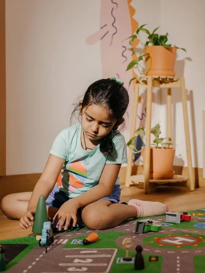 A child engaged in imaginative play with a road map and wooden toys. This form of play helps develop storytelling, spatial awareness, and real-world understanding.