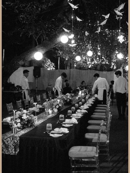 Another view of the beautifully set long table under a canopy of lights and hanging paper birds.