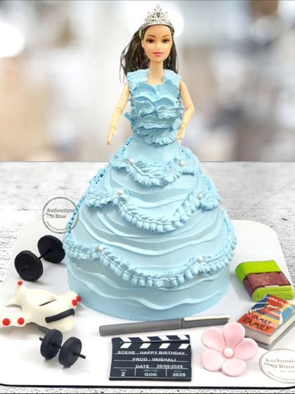 A classic Barbie doll cake where the cake itself forms her beautiful blue gown. We also included edible decorations representing her favorite things, like books and fitness.