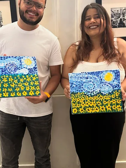 A couple proudly presenting their 'Starry Night' inspired paintings, making for a perfect creative date night.