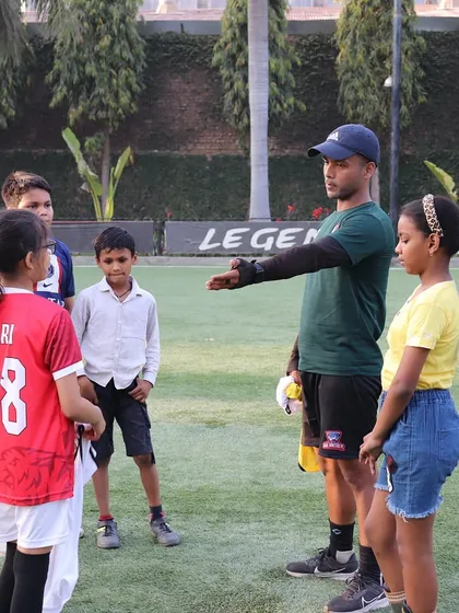 A coach instructing our young players, including girls, during a training session. We welcome all aspiring footballers.