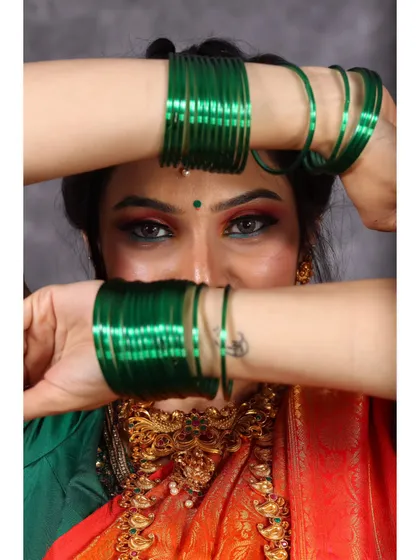 A creative close-up shot using green bangles to frame the model's face. This highlights the accessories as a key part of the traditional ensemble.