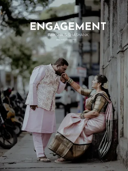 A classic, romantic pose from an engagement shoot on a city sidewalk. The groom kissing the bride's hand is a timeless gesture of love.