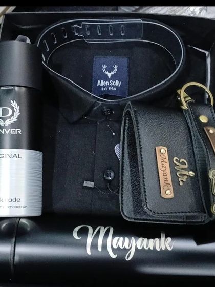 A sleek and modern all-black themed gift hamper. It contains a black Allen Solly shirt, a personalized wallet and keychain, a name bottle, and a Denver deodorant.