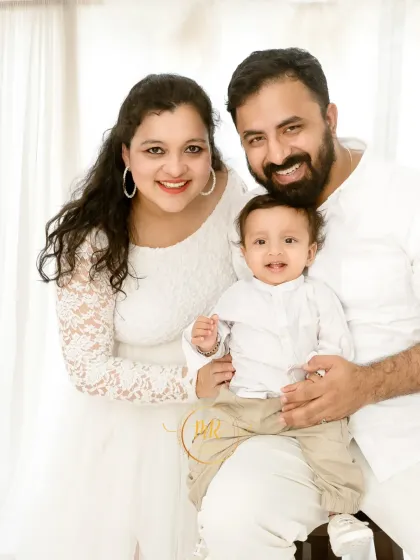 A bright and happy family portrait with both parents and their baby boy, all dressed in white. I always encourage parents to join in, as these moments of connection are truly priceless.