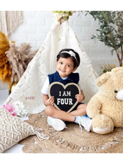 "I am Four". Using signs is a great way to mark a birthday milestone. This confident little girl is so proud to be celebrating her fourth birthday.