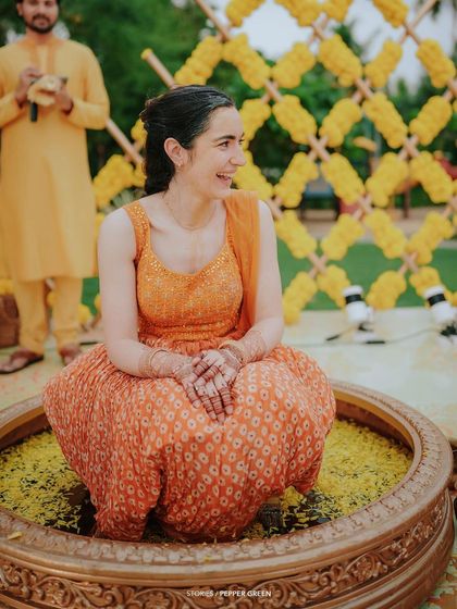 The bride, Eli, seated in a large decorative bowl filled with marigold petals for her Haldi. This unique tradition makes for beautiful and memorable footage.